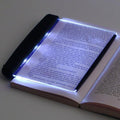 Open book with a LED reading light illuminating the text on a plain background