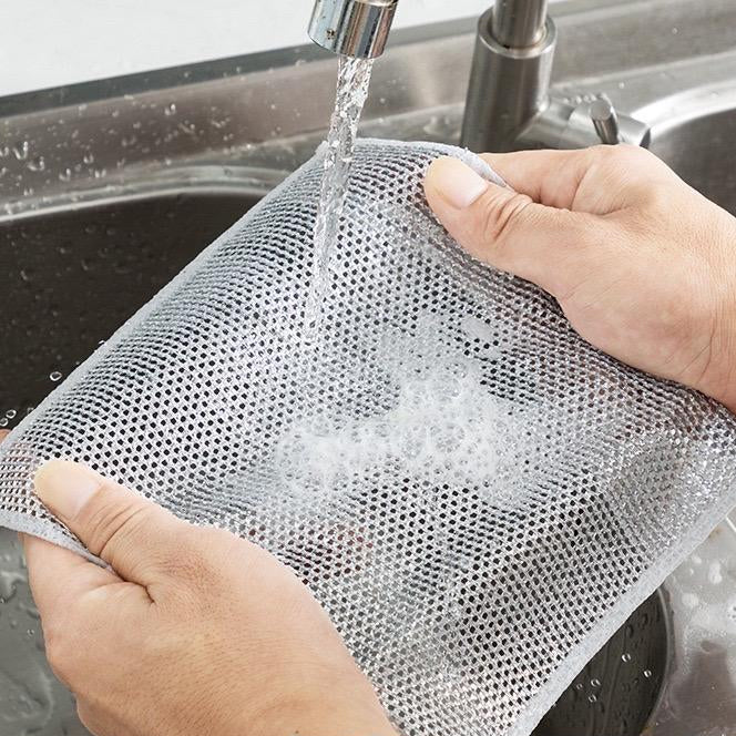 Person washing a mesh bag under running water in a sink with text on the screen.